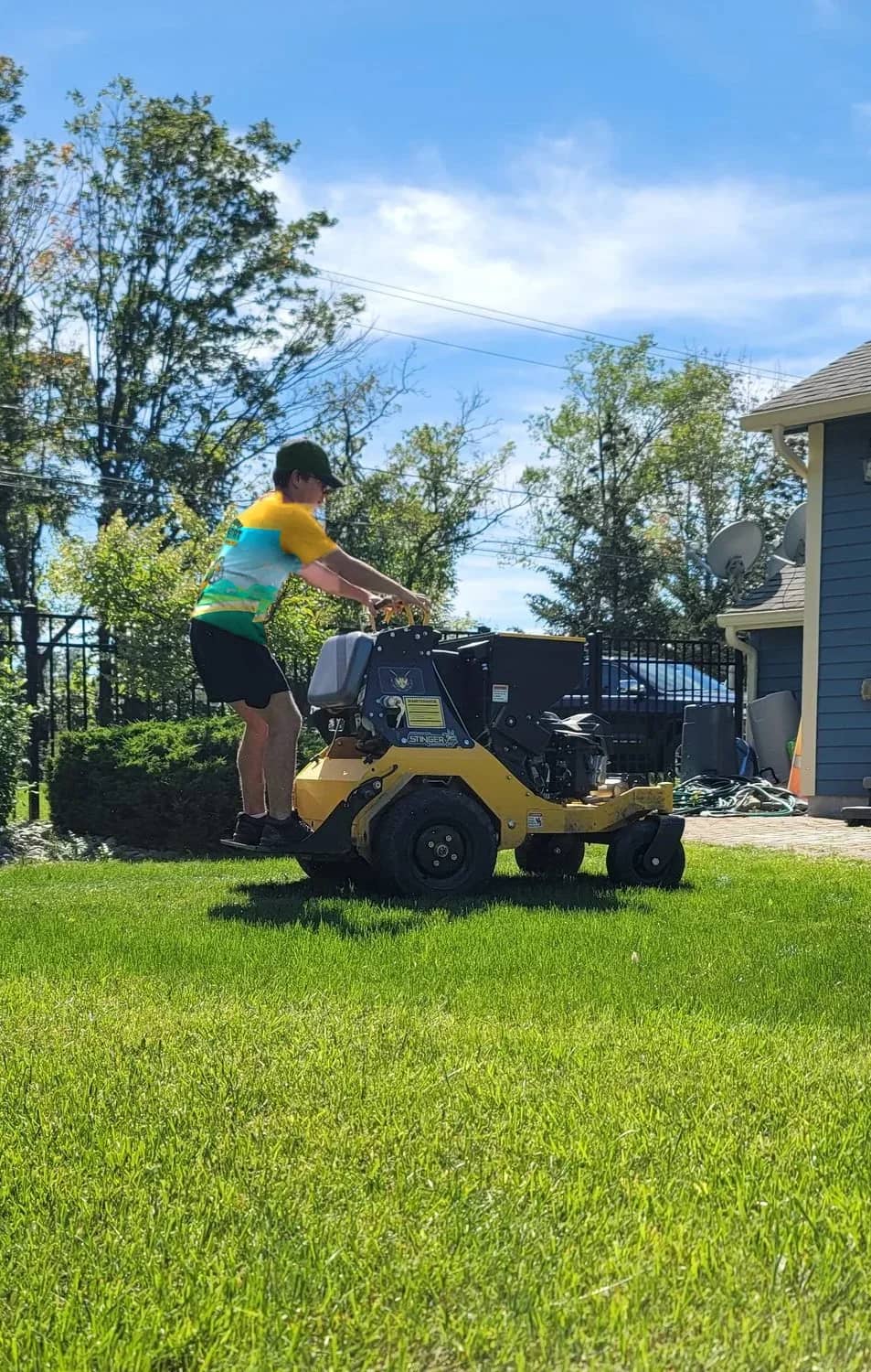 A Happy Habitat technician running an aerator across a client's lawn.