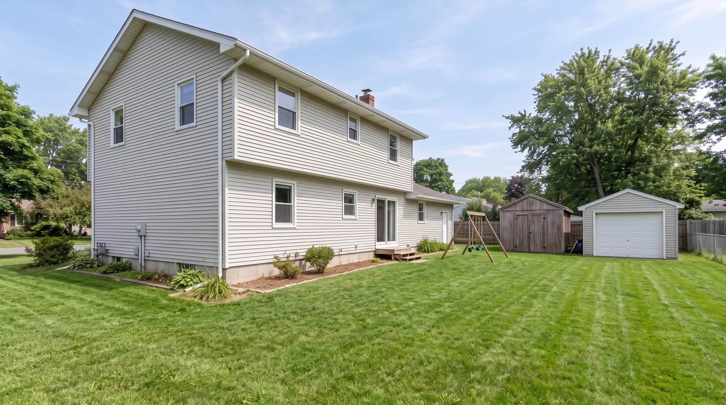 The back and side of a two-story home with a swing set, a shed and a detached garage, showing what each exterior pest level covers.